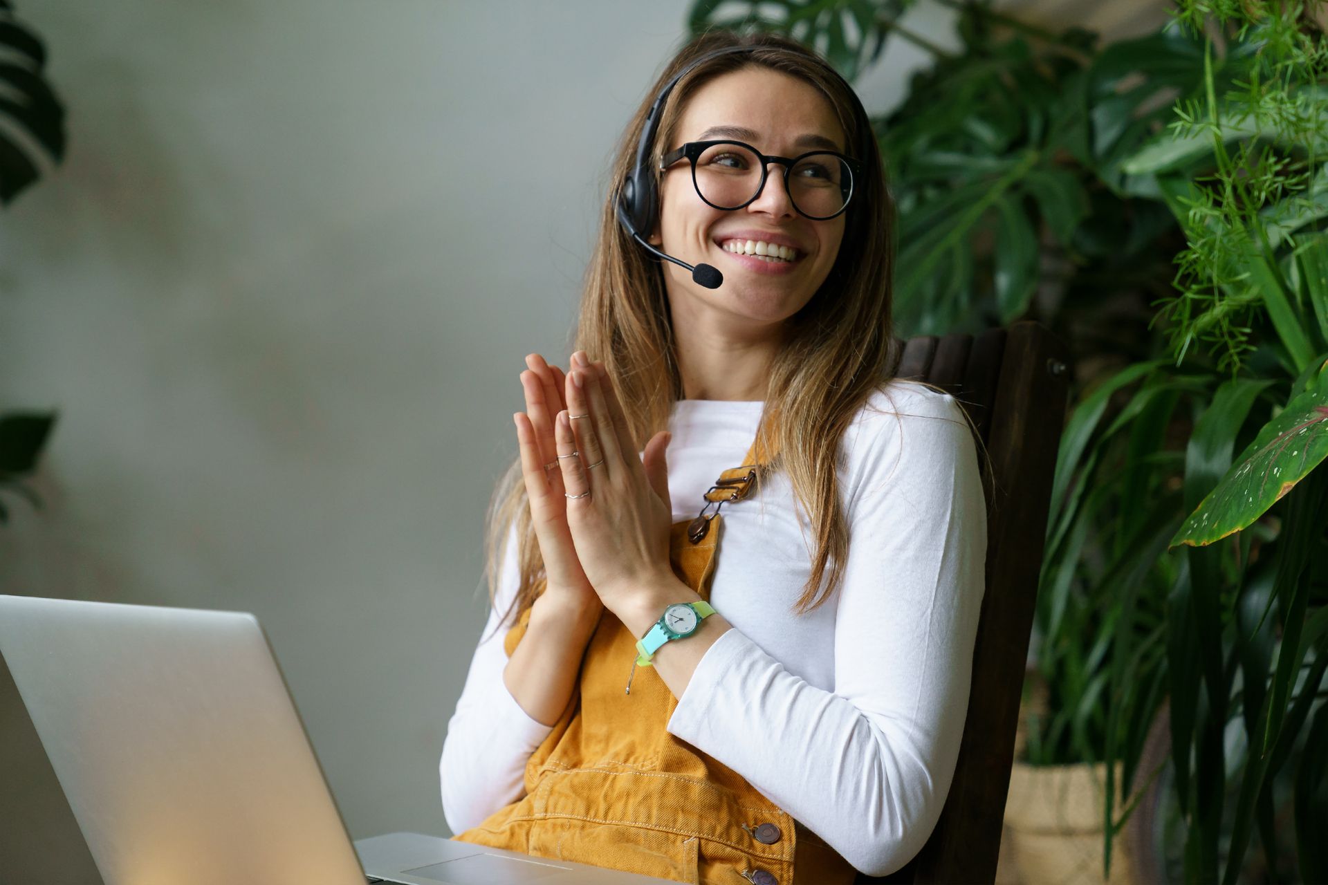 Woman with headset smiles while working on a laptop, symbolizing customer service at CANCOM Austria.